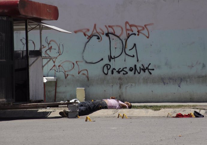Un cadáver bajo un grafiti con las iniciales del Cártel del Golfo