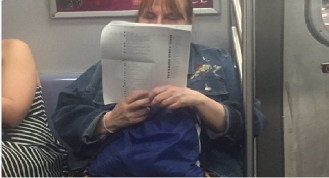 Una mujer se imprime comentarios de Fcebook para leerlos en el metro