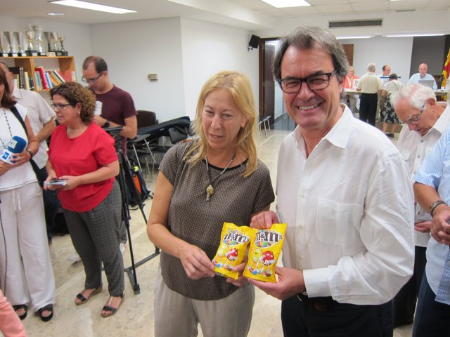 Neus Munté y Artur Mas (PDC) sostienen dos paquetes de M&M's