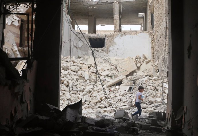 Un niño pasea entre los restos de un edificio destruido en Alepo (Siria)