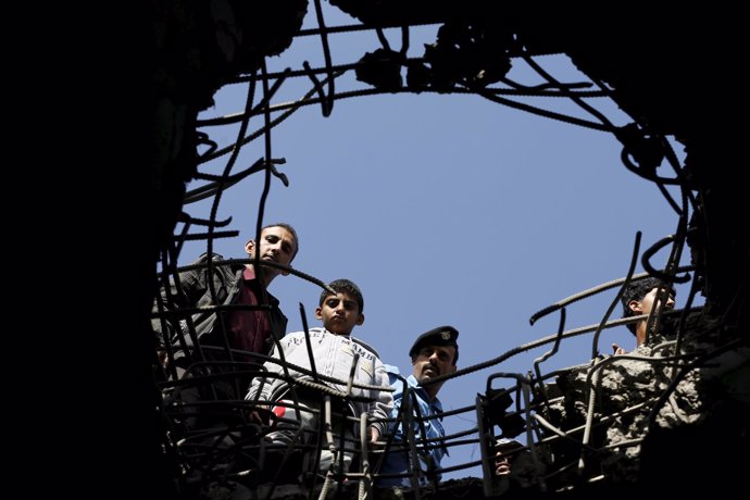 Yemeníes miran a través de un agujero dejado por una bomba en Saná