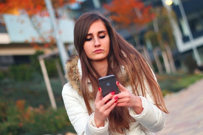 Joven chica adolescente smartphone teléfono iPhone texto mensajería WhatsApp