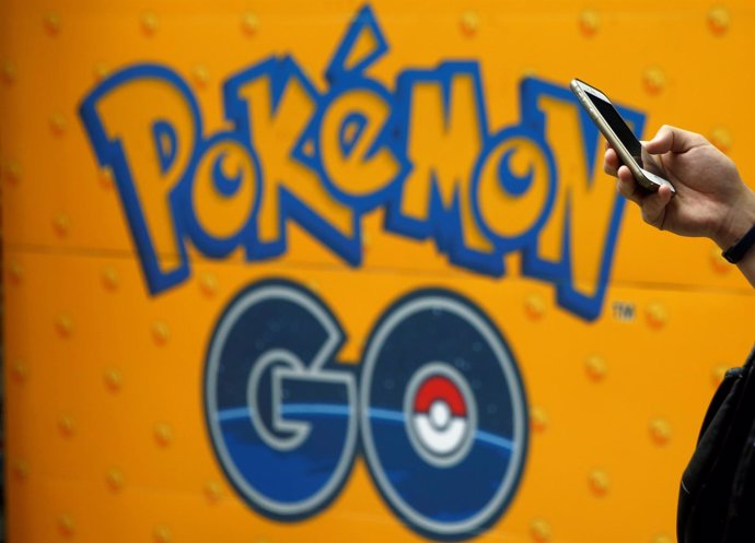 Un hombre usa el móvil frente a un anuncio de Pokémon Go
