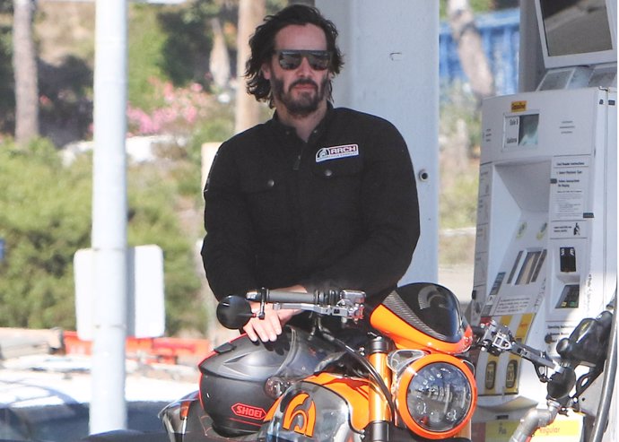 Keanu Reeves con su moto en una gasolinera.