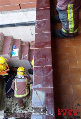 Bomberos trabajando en el saneamiento de un balcón interior en Cornellà