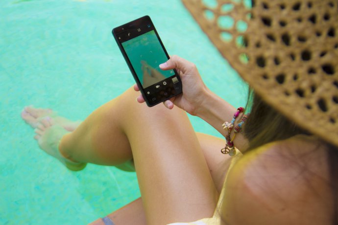 Una chica en la piscina usando el móvil
