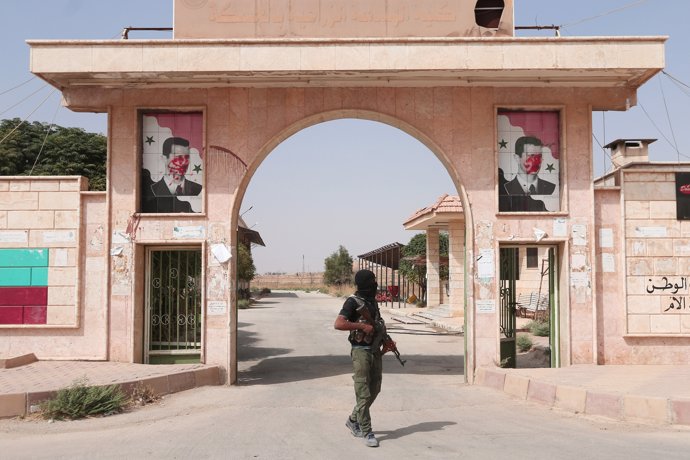 Miliciano kurdo en Hasaka delante de retratos de Al Assad