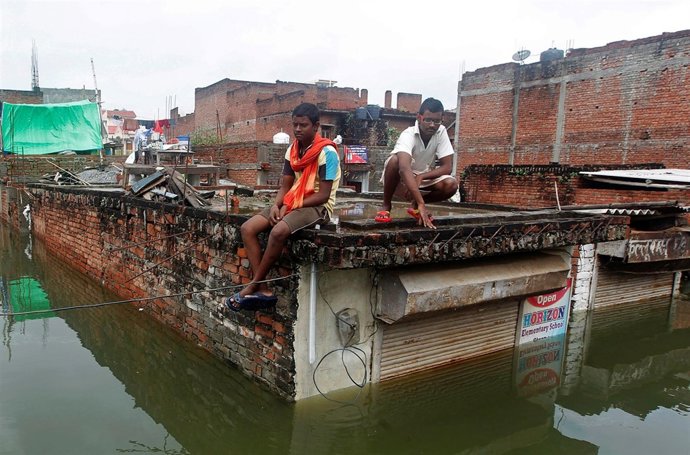 Dos jóvenes miran la inundación en el tejado de una tienda