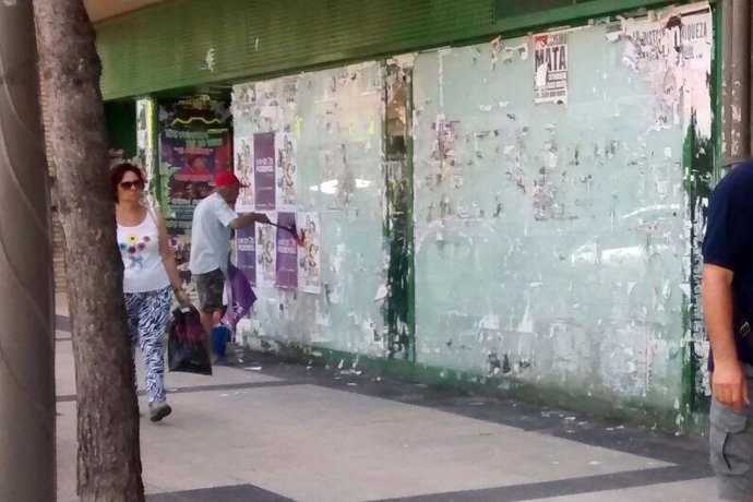 Ciudadano colgando un cartel de Unidos Podemos en un lugar indebido