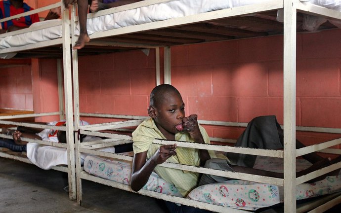 Un niño haitiano sentado sobre su cama en un orfanato en Puerto Príncipe.