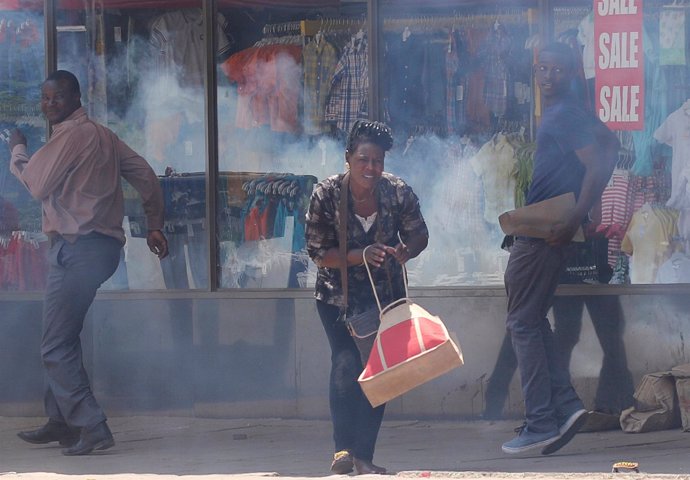 Varios ciudadanos huyen del gas lacrimógeno lanzado por la Policía en Harare.