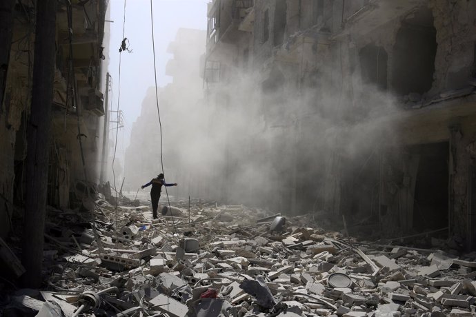 Una persona camina entre escombros en una zona rebelde de Alepo