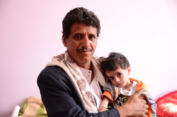 Un padre yemení con su hijo desnutrido en brazos