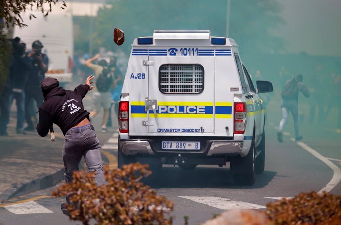 Un manifestante apedrea un coche de Policía en las protestas universitarias