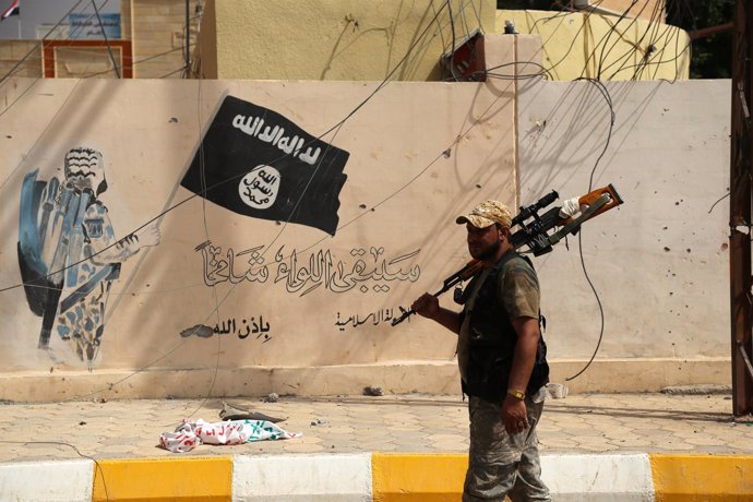 Un militar iraquí junto a la bandera de Estado Islámico en Shirqat