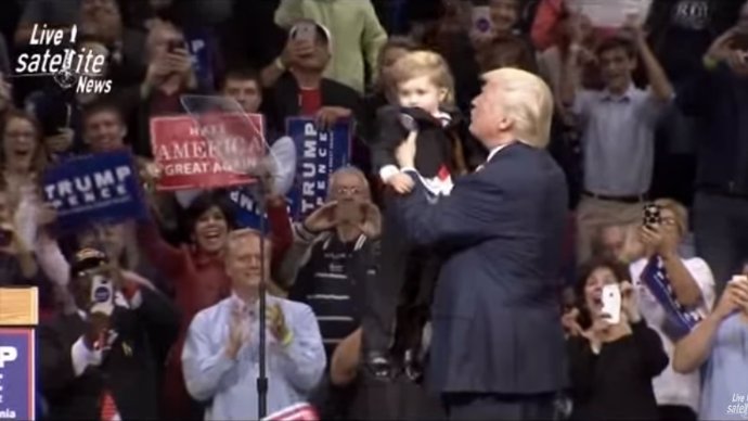 Trump sujeta a un niño disfrazado como él durante un mitin