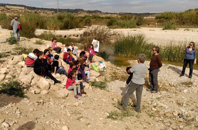 Un grupo de niños atiende las indicaciones de un monitor, cerca del río.