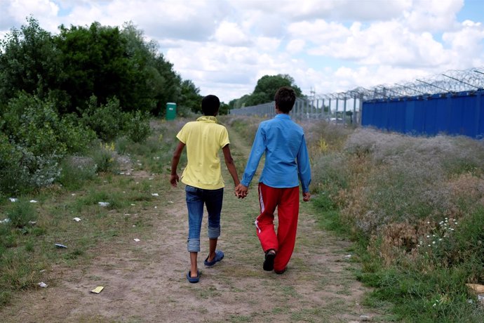Menores refugiados caminan junto a la valla fronteriza en Serbia