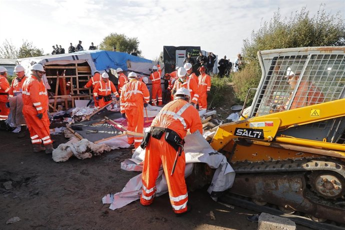 Un grupo de operarios retira tiendas en el campamento de Calais