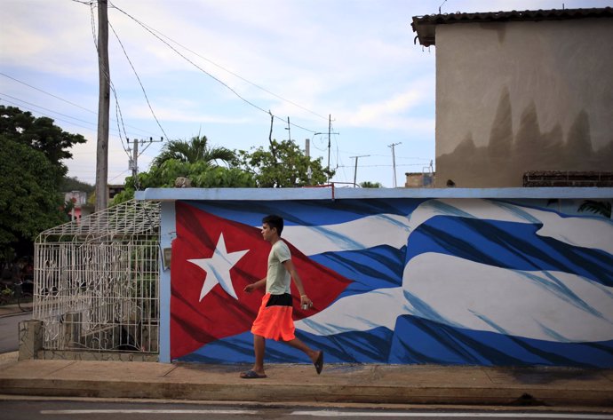 Un hombre camina junto a la bandera de Cuba en Holguín