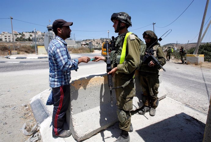 Un militar israelí pide la documentación a un palestino en Cisjordania.