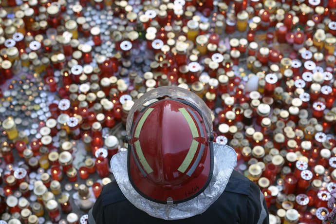 Un bombero junto a un memorial por las víctimas del incendio