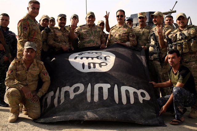 Soldados iraquíes posan con la bandera de Estado Islámico