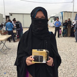 Una mujer iraquí sonríe mostrando su radio cerca de Mosul, Irak