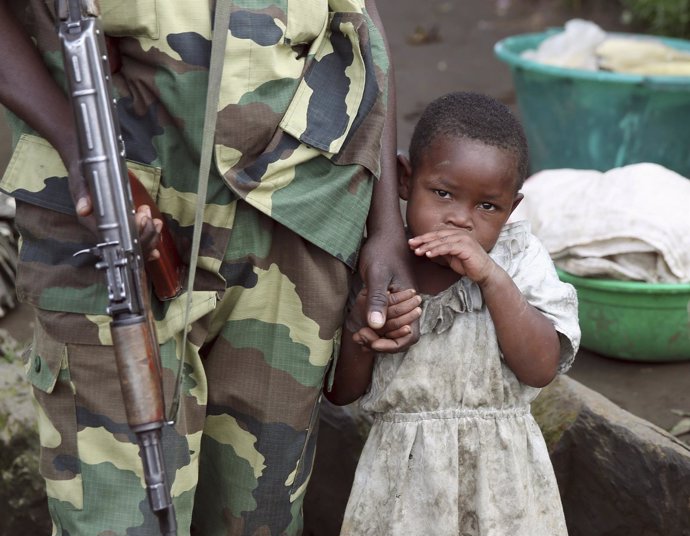 Una niña junto a un soldado del M-23