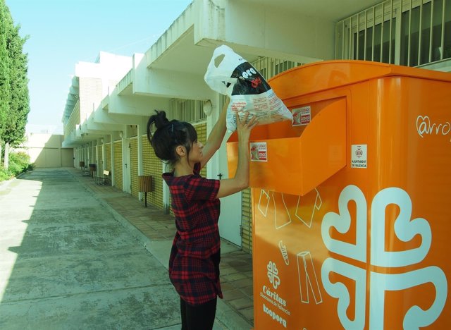 Una mujer introduce ropa en un depósito de Cáritas