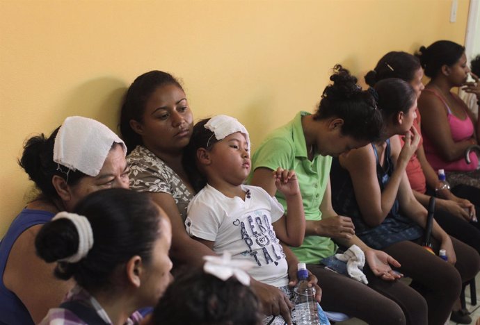 mujeres y niños esperando en una consulta médica para ser atendidos.