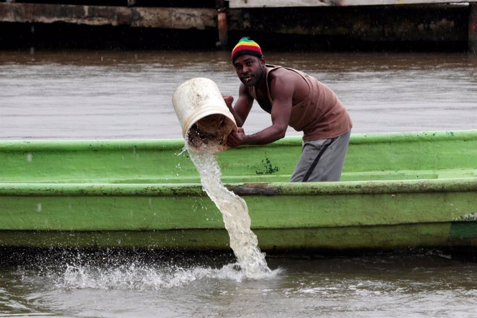 Un hombre achica agua de una barca ante la llegada del huracán 'Otto'