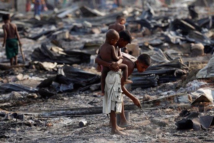 Niños rohingya buscan entre restos de casas incendiadas en Rajine, Birmania