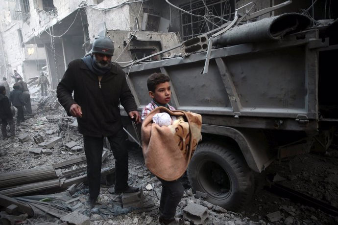 Un niño con un bebé tras un bombardeo en Duma, alrededores de Damasco