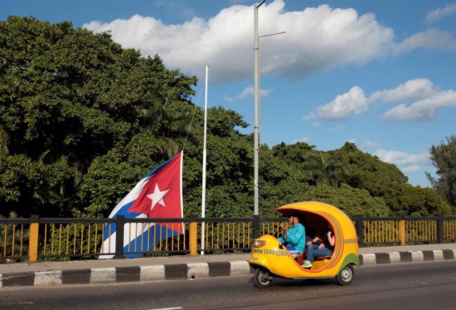 Un cocotaxi y la bandera cubana a media asta por la muerte de Fidel Castro