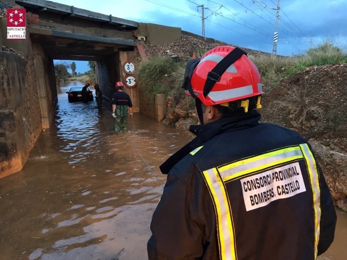 Los bomberos rescatan un vehículo atrapado por la lluvia bajo un puente