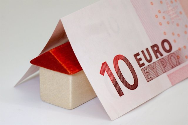 Billete de diez euros encima de una casa de madera