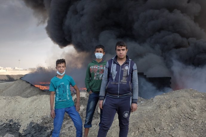 Varios niños juegan junto a una nube de humo en Qayara, Irak.