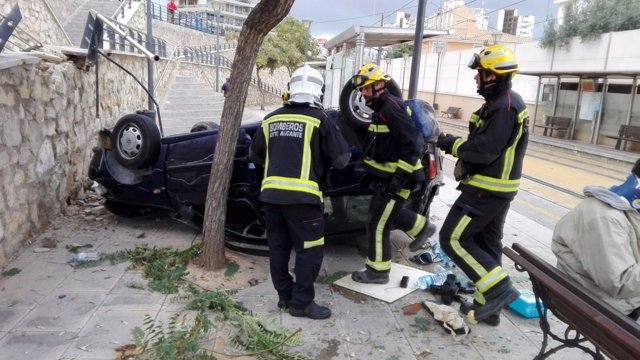 Los bomberos junto al coche que ha caído a la parada del TRAM