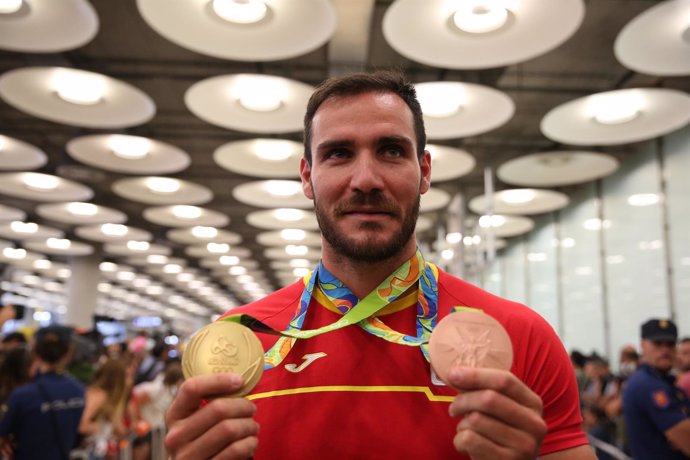 Saul Craviotto enseña sus medallas a la llegada a España