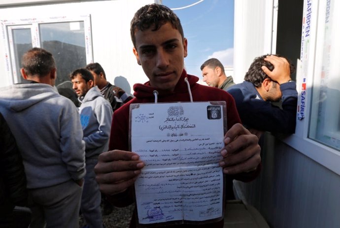 Un joven sostiene un certificado emitido por el EI