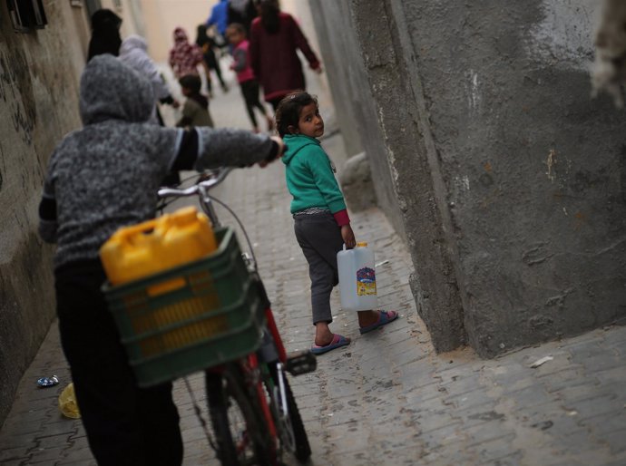 Niña palestina recoge agua embotellada en Gaza