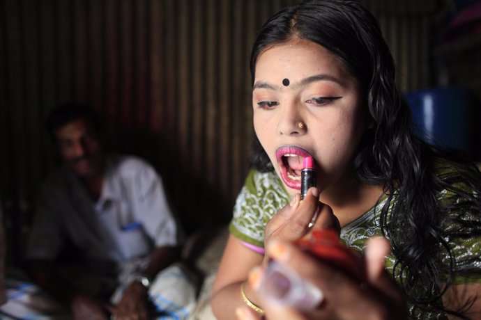 Un joven prostituta de 16 años se pinta los labios en un burdel de Bangladesh