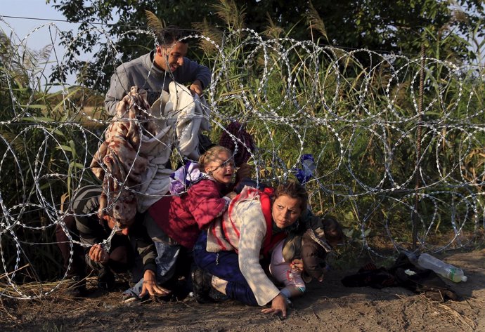 Refugiados sirios cruzan la valla en la frontera con Hungría