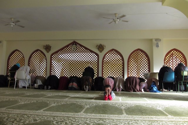 Niño junto a mujeres rezando en una mezquita