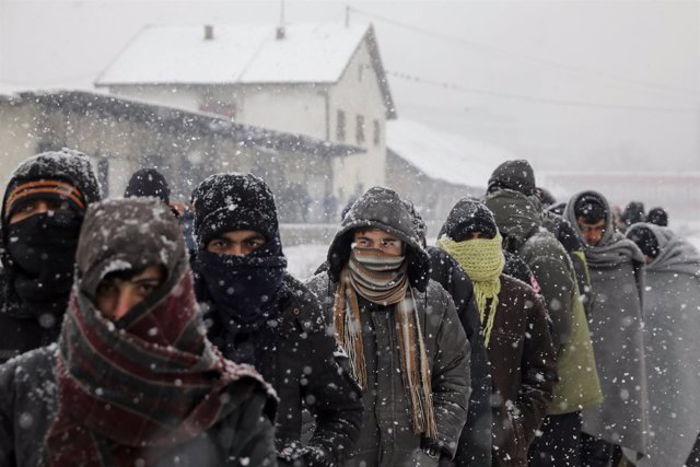 Refugiados hacen cola bajo la nieve para comer