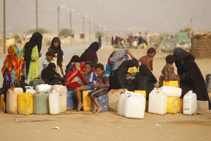 Un grupo de mujeres y niños recolectan agua en un campo de desplazados en Yemen.