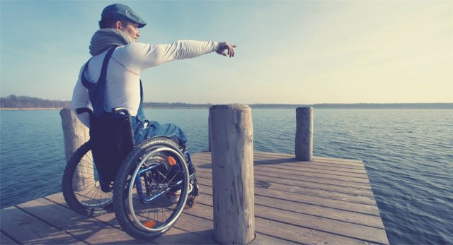 Un joven en silla de ruedas señala el horizonte