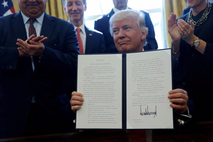 Donald Trump firma una orden rodeado de empresarios