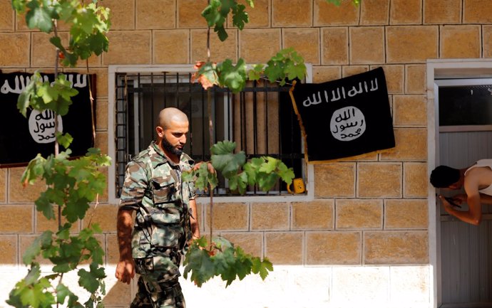 Miliciano del Ejército Libre Sirio en Jarablus ante banderas del Estado Islámico
